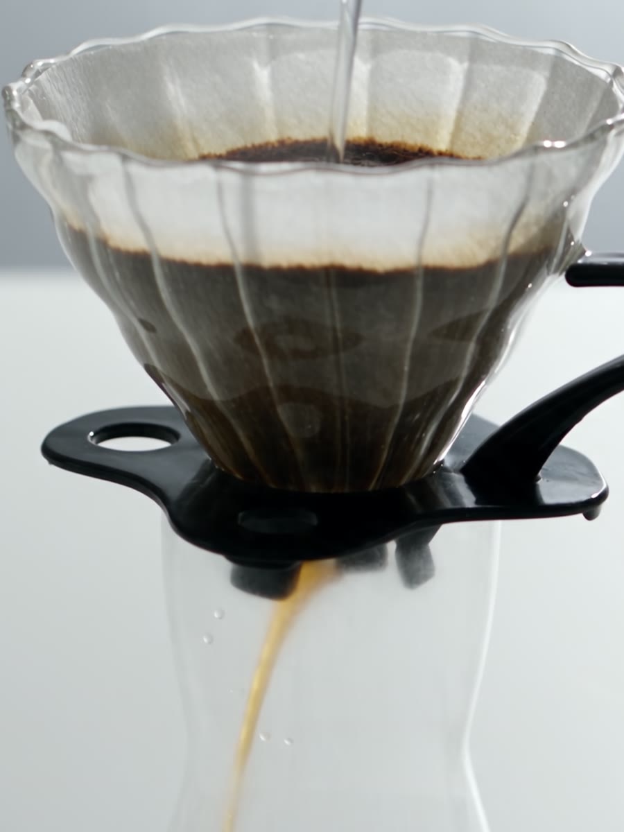 Coador V60 de vidro sobre decanter de borossilicato durante a extração do café.
