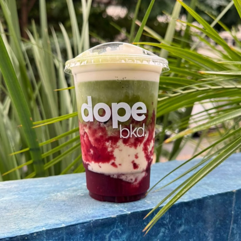 Matchá gelado em copo dope bkd. com calda de frutas vermelhas no fundo.