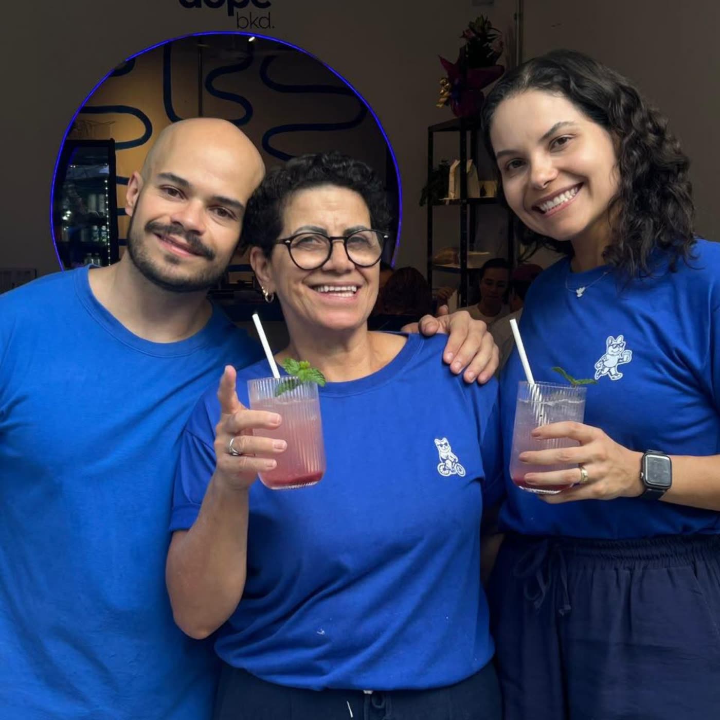 Os três sócios da Dope Baked — mãe, filho e filha — juntos no salão, de camiseta azul da marca.
